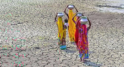 Women carry pots filled with drinking water on their heads through a dry pond, in Nadia, Monday, April 17, 2023, as South Bengal area is facing a drought-like-situation due to heatwave. (PTI)