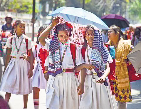 Students use scarves and umbrellas to shield themselves from the hot summer sun, while returning from school, in Ranchi on Wednesday | PTI