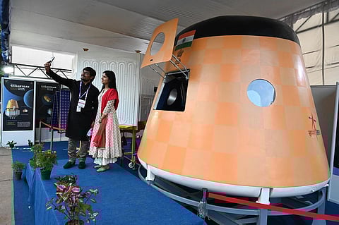 Visitors take a selfie with a scale model of Gaganyaan spacecraft. (Photo | Nagaraja Gadekal, EPS)