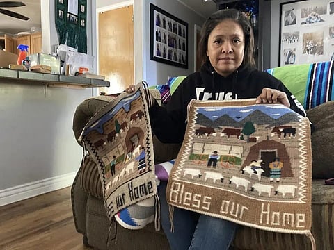 FILE - Seraphine Warren poses for a photo in her home in Tooele, Utah, on Sept. 23, 2021, with a rug made by her aunt, Navajo rug weaver Ella Mae Begay. (Photo | AP)