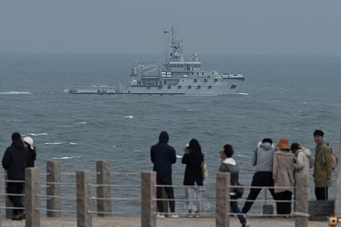 A PLA Navy tugboat sails in the Taiwan Strait, past tourists on Pingtan island, the closest point to Taiwan, in China's southeast Fujian province on April 7, 2023. (Photo | AFP)