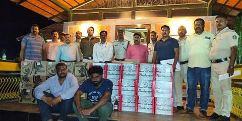 Officials pose with the seized cash and alcohol in Chitradurga. (Express Photo)