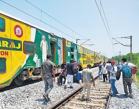 Passengers walk on the tracks with their luggage to board the unaffected coaches.