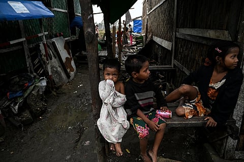 Children sit outside damaged houses at Basara refugee camp in Sittwe on May 16, 2023, after cyclone Mocha made a landfall. (Photo | AFP)