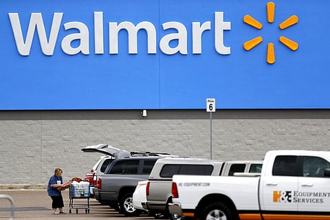 A woman pulls groceries from a cart to her vehicle outside of a Walmart store in Pearl, Miss. (File Photo | AP)