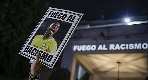 A protester holds up a photo of Brazilian star Vinicius Jr and a message that reads in Portuguese; 'Fight racism' during a protest against racism in Sao Paulo, Brazil, May 23, 2023. (Photo | AP)