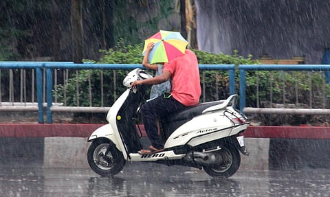 Braving downpour, a man goes on a scooter with his child in Vizag. (Photo | G Satyanarayana, EPS)