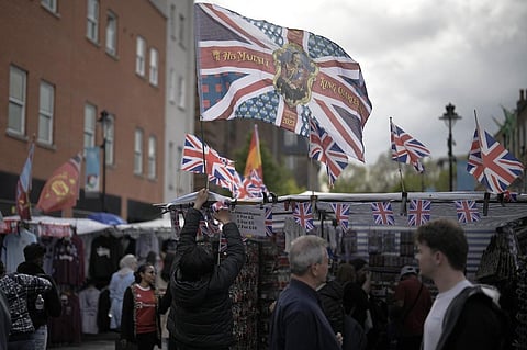 A vendor decorates his shop with a flag for the Coronation of King Charles III in London Friday, May 5, 2023. (Photo | AP)