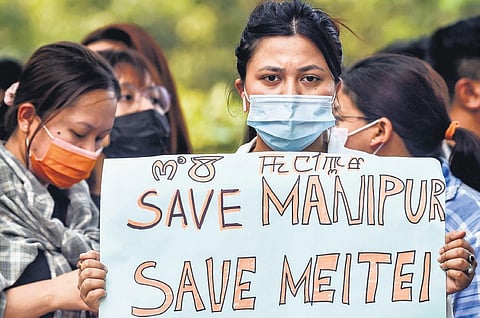 A woman from Manipur displays a placard during a protest at Jantar Mantar in New Delhi on Friday . (Photo| PTI)