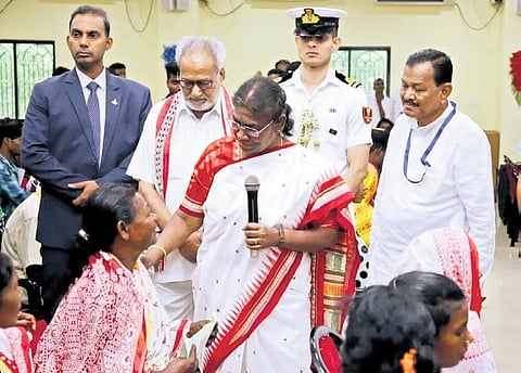 President Murmu interacting with women from PVTGs at the university on Saturday, (left) A student from Bhadrak displaying a portrait of Murmu | Express