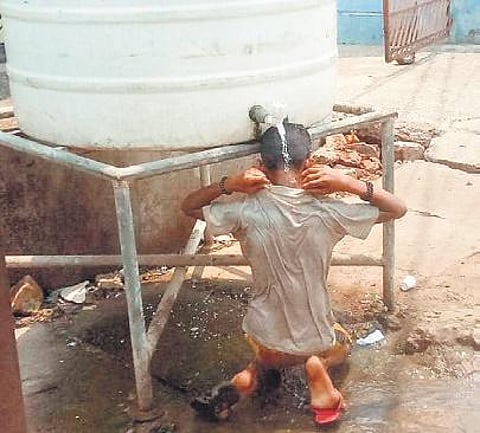 A boy bathing under a roadside water tank to beat the heat in Cuttack | Express