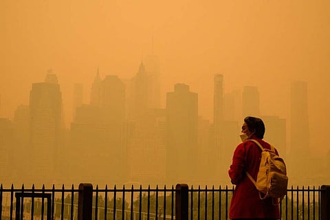 An orange-tinged smog caused by Canada's wildfires shrouded New York causing residents to don face masks. (Photo | AFP)