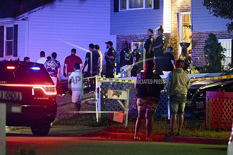 Police stand among a crowd outside a home where multiple people were shot in Annapolis. (Photo | AP)