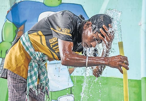 A man splashes water on his head from a pipe at a construction site under Jagatpur flyover in Cuttack, on Sunday(Photo | EPS/ Debadatta Mallick)