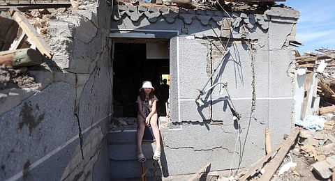 A young child sits in the window frame of the remains of her home in the aftermath of a Russian attack on Kramatorsk. (Photo | AFP)