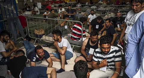 Survivors of a shipwreck sit inside a warehouse where are taking shelter at the port in Greece's Kalamata town.(Photo | AP)
