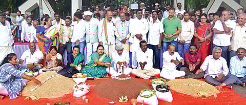 Congress leaders with mounds of foodgrains during a mock harvest protest in Tumakuru on Sunday