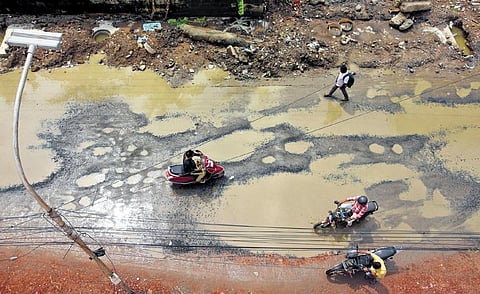 Motorists and pedestrians negotiate a damaged road in Madipakkam on Tuesday morning | Ashwin Prasath