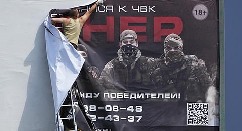A man takes down a poster reading 'Join us at Wagner' above a highway on the outskirts of St. Petersburg, Russia, Saturday, June 24, 2023. (Photo | AP)