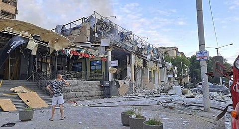 In this photo provided by the Ukrainian Donetsk Regional Administration, a man stands on a street in front of a shop and restaurant RIA Pizza destroyed by a Russian attack in Kramatorsk.(Photo | AP)