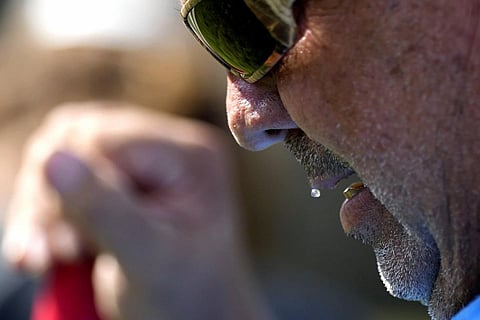 Sweat rolls off the lip of Robert Harris as he digs fence post holes, June 27, 2023. (Photo | AP)