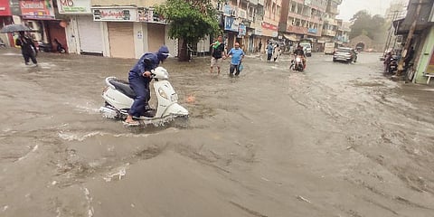 Commuters move through a waterlogged road after heavy monsoon rains, in Jamnagar on June 30, 2023 (Photo | PTI)