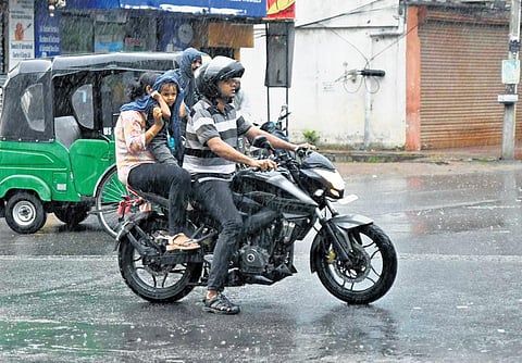 A motorist drives as his wife holds their child amidst a sudden downpour at Kondapur on Sunda| Vinay madapu