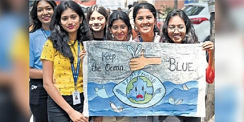 BMS Degree College students hold a poster on World Environment Day in Bengaluru on Monday