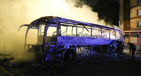 Firefighters use a water hose on a burnt bus in Nanterre, outside Paris. (Photo | AP)
