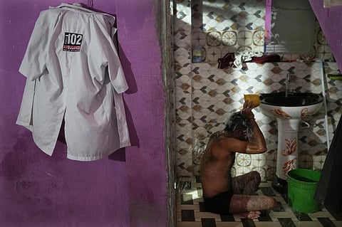 Sunil Kumar Naik, an ambulance driver, bathes as he gets ready for the day, in Banpur, Uttar Pradesh. (Photo | AP)