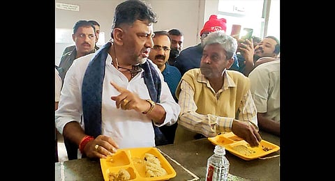 Deputy Chief Minister DK Shivakumar, during an inspection of an Indira Canteen, interacts with a customer over breakfast, in Bengaluru on Sunday. (Photo | Express) 