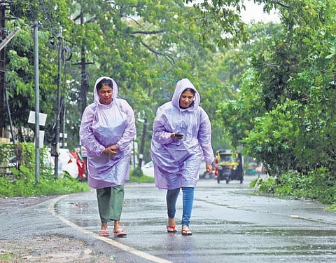 Women wearing raincoats walk on a road in Kadavanthra under heavy rain. (Photo | TP Sooraj)