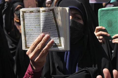A demonstrator holds up a copy of the Quran, Islam's holy book, during a protest against the burning of a Quran in Sweden, in front of the Swedish Embassy in Tehran, Iran. (Photo | AP)