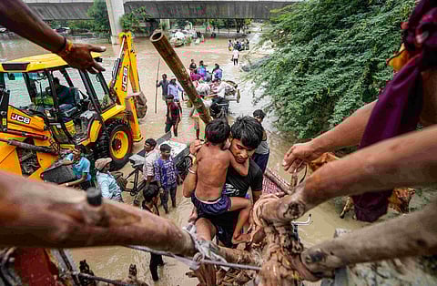 People from low-lying areas around the Yamuna river help one another relocate to a safer place after their houses were submerged in the swollen river, in New Delhi, Wednesday, July 12, 2023.(PTIPhoto)