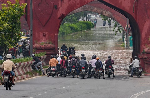 Commuters wait to make through a flooded road near the Red Fort as the swollen Yamuna river floods low-lying areas (Photo | PTI)