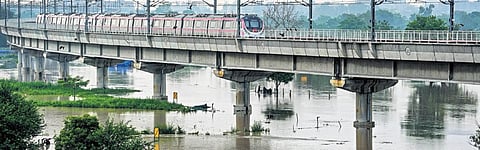A Metro train crosses the Yamuna river, flowing far above the danger mark, on Wednesday | PTI