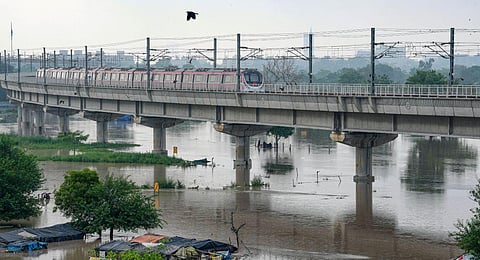 A Delhi Metro train passes by as the swollen Yamuna river floods low-lying areas, in New Delhi, Wednesday, July 12, 2023. (Photo | PTI)