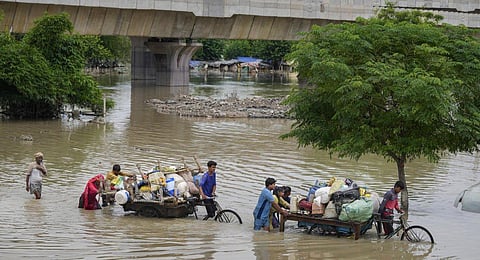 People from low-lying areas carry their belongings while relocating to a safer place after the Yamuna river inundated the nearby areas in New Delhi, Sunday, July 16, 2023. (Photo | PTI)
