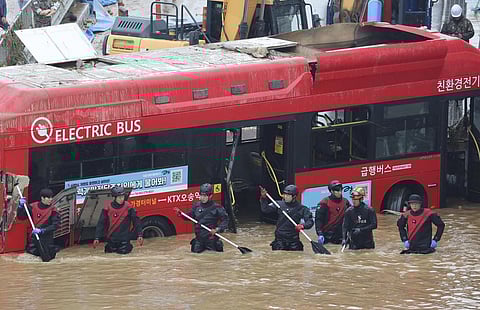 Rescuers conduct a search operation along a road submerged by floodwaters leading to an underground tunnel in Cheongju. (Photo | AP)