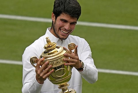 Spain's Carlos Alcaraz celebrates with the trophy after beating Serbia's Novak Djokovic to win the final of the men's singles on day fourteen of the Wimbledon tennis championships in London. (AP)