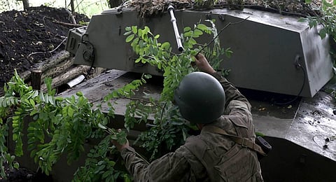 A Ukrainian artilleryman uses tree branches to camouflage a military vehicle at the frontline near the town of Bakhmut, Donetsk region. (Photo | AFP)