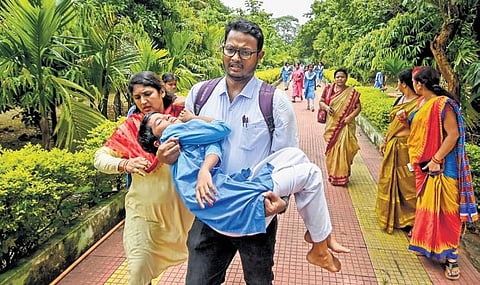 A teacher carries a girl student who fainted during the protest I Express