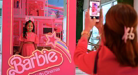 A child poses for a photo inside a life-sized doll box after watching the 'Barbie' film. (Photo | AFP)