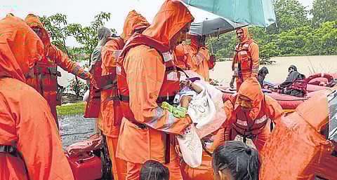 NDRF personnel carry an infant during a rescue operation for people stuck in flood-hit village in Poladpur, Raigad in Maharashtra on Wednesday | pti