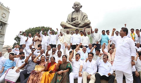 BJP MLAs protest the suspension of 10 party lawmakers from the Legislative Assembly in front of Vidhana Soudha in Bengaluru on Thursday. (Photo | Express)