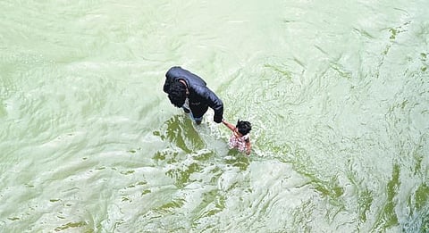 A man and his daughter wade through a flooded road at Gajularamaram in Hyderabad on Friday | Gajularamaram