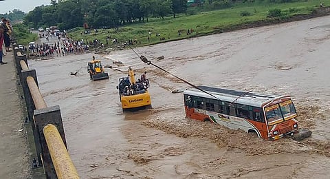 An earthmover helps rescue a Uttar Pradesh State Road Transport Corporation (UPSRTC) bus that got stuck in the strong water current of the Kotawali river. (Photo | PTI)