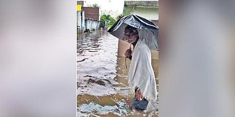 An elderly man wades through knee-deep water that inundated several colonies in Adilabad on Saturday