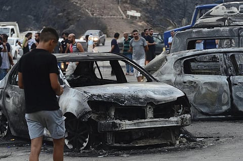 People inspect burnt vehicles after raging wildfires in Bouira, 100 km from Algiers, Algeria, July 24, 2023. (Photo | AP)