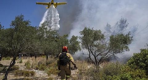 An aircraft drops water over a wildfire in Vati village, on the Aegean Sea island of Rhodes. A third successive heat wave in Greece pushed temperatures back above 40 degrees Celsius. (Photo | AP)